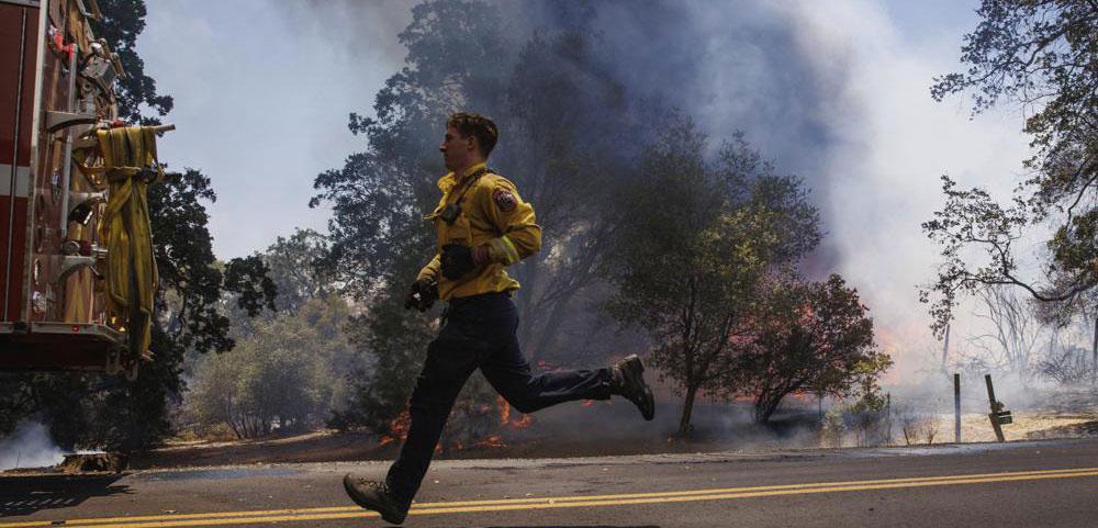 A firefighter runs as the Oak Fire burns on Triangle Road in unincorporated Mariposa County, Calif., Saturday, July 23, 2022. (Ethan Swope/San Francisco Chronicle via AP)