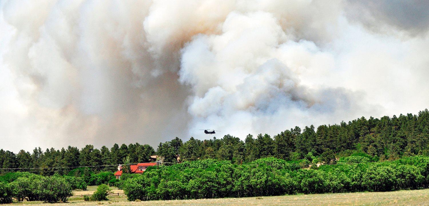 Pilots and crewmembers of the 2nd General Support Aviation Battalion, 4th Aviation Regiment, 4th Combat Aviation Brigade, 4th Infantry Division, go into the thick smoke to release water onto the burning fires during their bambi bucket mission at Black Forest, Colo., June 12, 2013. (Photo by Sgt. Jonathan C. Thibault, 4th Combat Aviation Brigade Public Affairs Office, 4th Infantry Division; The U.S. Army)