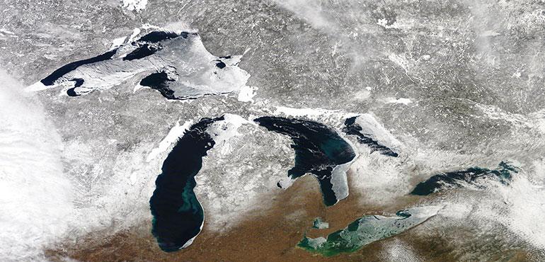 In this March 12, 2019 satellite photo provided by NOAA, shows the Great Lakes in various degrees of snow and ice. A scientific report says the Great Lakes region is warming faster than the rest of the U.S., which likely will bring more flooding and other extreme weather events such as heat waves and drought.