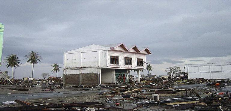 Trash and debris litter the streets near a standing house in downtown Banda Aceh, Sumatra, Indonesia, following the 2004 Indian Ocean earthquake and tsunami that struck the area on December 26, 2004. (Michael L. Bak via Wikimedia Commons)