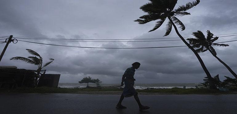 Dark clouds hover as a man walks along a street in Colombo, Sri Lanka, Wednesday, Nov. 27, 2024. (AP Photo/Eranga Jayawardena)