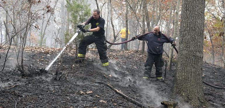 Firefighters work to put out a brush fire, Tuesday, Oct. 29, 2024, in Salem, Mass. (AP Photo/Steven Senne, File)