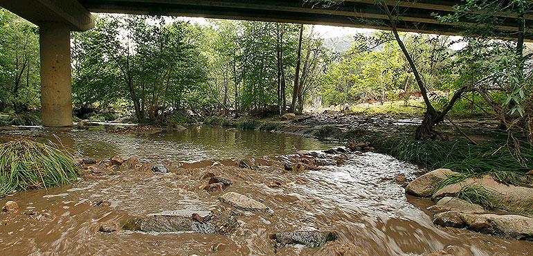 Muddy floodwaters of the East Verde River flow under a bridge where one victim of the flash flood was found during a search and rescue operation by the Gila County Sheriff's Office on Sunday, July 16, 2017, in Payson, Ariz. (AP Photo/Ralph Freso)