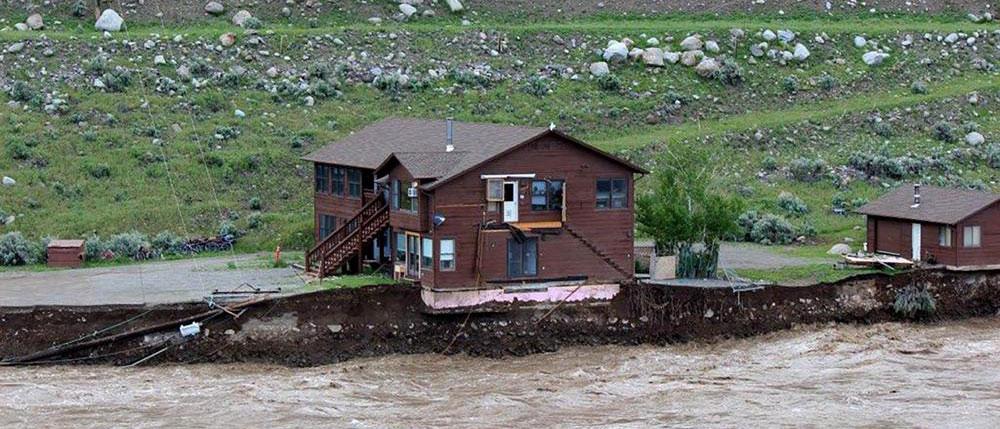 The flooding Yellowstone River undercuts the river bank, threatening a house and a garage in Gardiner, Mont., on June 13, 2022. (Sam Glotzbach via AP)