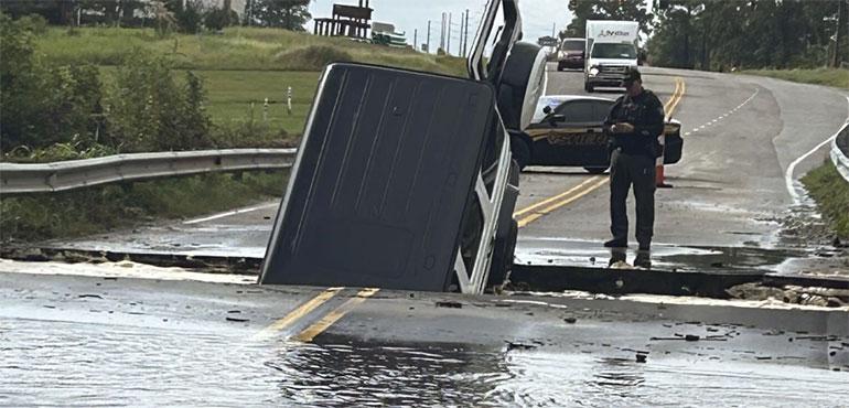 This photo provided by Brunswick County Sheriff’s Office shows a police officer checking on a vehicle that fell into a sinkhole on a highway in Brunswick County, N.C., after a storm dropped historic amounts of rain, Monday, Sept. 16, 2024. (Brunswick County Sheriff’s Office via AP)