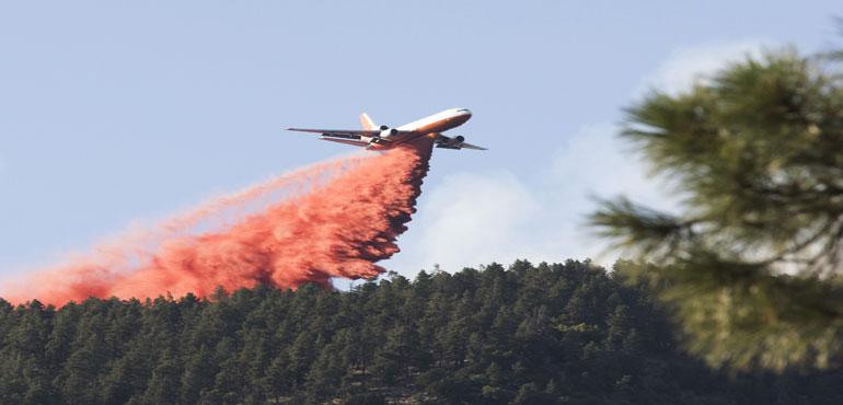 In this Sunday, July 21, 2019, photo, a tanker releases a wave of fire retardant into the crest of a wildfire line in Flagstaff, Ariz. (Ben Shanahan/Arizona Daily Sun via AP)