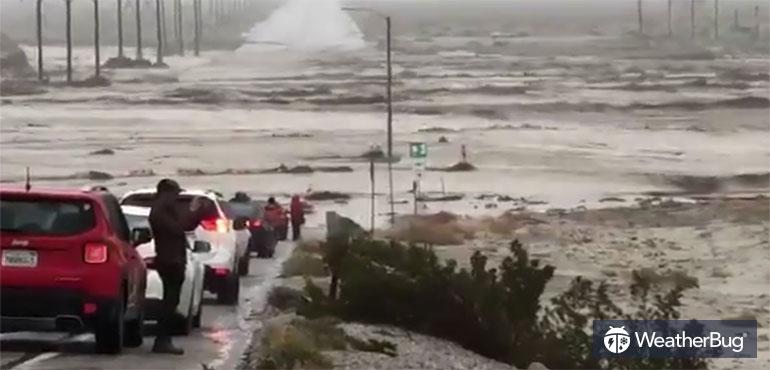 Water rushes over the roadway in Palm Springs, Calif.