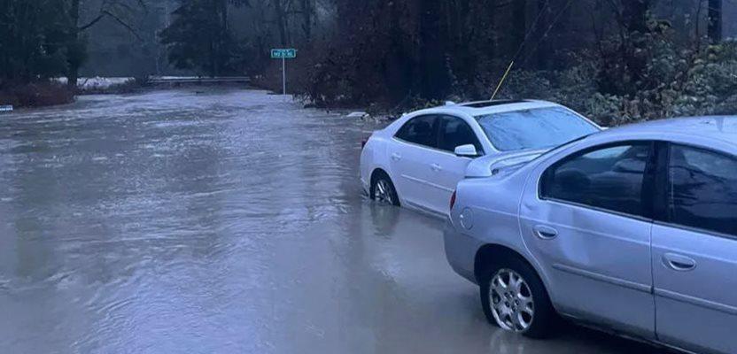In this photo provided by Kira Mascorella, cars drive through flood waters in Granite Falls, Wash., Tuesday, Dec. 5, 2023. (Kira Mascorella via AP)