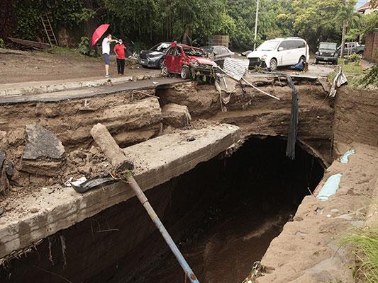 Locals look at the damage caused by floods after the Acelhuete River flooded in San Salvador, El Salvador, Sunday, May 31, 2020. According to the Ministry of the Interior, at least seven people died across the country after two days of heavy rains. (AP Photo/Salvador Melendez)