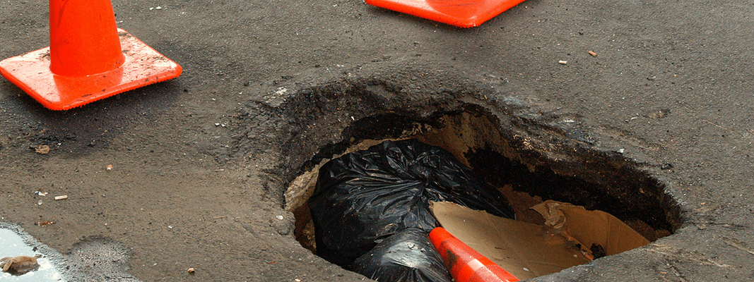 A pothole big enough to hold a traffic cone and garbage. (David Shankbone, Wikimedia Common)