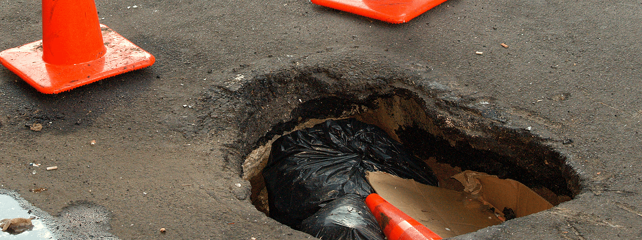 A pothole big enough to hold a traffic cone and garbage. (David Shankbone, Wikimedia Common)