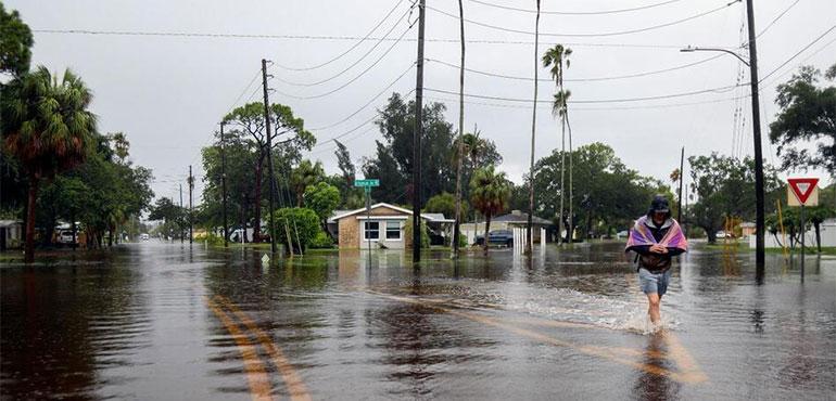 Carter Grooms, 25, of Tampa, wades through the streets in the Shore Acres neighborhood of St. Petersburg, Fla., Monday morning, Aug 5, 2024, as Hurricane Debby passed the Tampa Bay area offshore. (Dylan Townsend/Tampa Bay Times via AP)