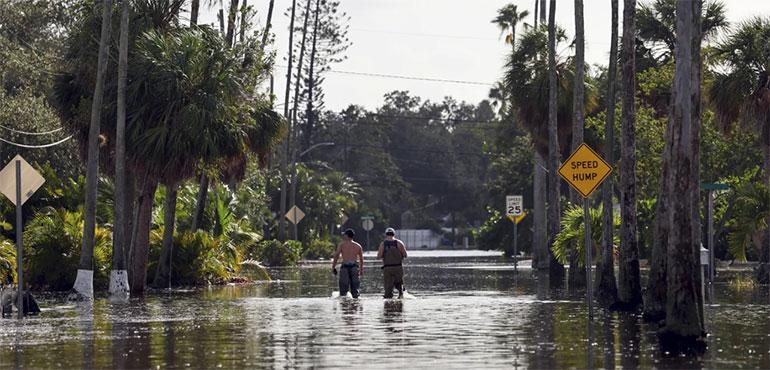 Men walk down a street flooded by Hurricane Helene in the Shore Acres neighborhood Sept. 27, 2024, in St. Petersburg, Fla. (AP Photo/Mike Carlson, File)