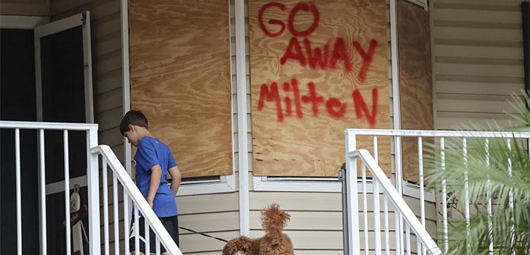 Noah Weibel and his dog Cookie climb the steps to their home as their family prepares for Hurricane Milton on Monday, Oct. 7, 2024, in Port Richey, Fla. (AP Photo/Mike Carlson)