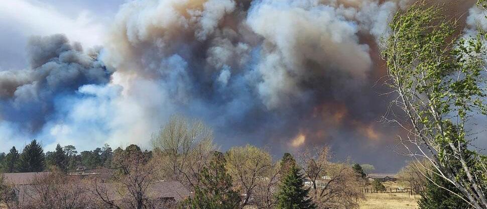 Smoke from a wind-whipped wildfire rises above neighborhoods on the outskirts of Flagstaff, Ariz., on Tuesday, April 19, 2022. (Sean Golightly/Arizona Daily Sun via AP)