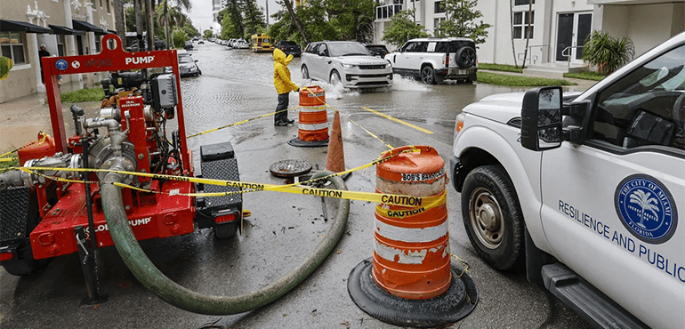 A City of Miami Public Works employee waves towards a vehicle driving through a flooded street in Edgewater along N.E. 23rd Street in Miami. Wednesday, June 12, 2024 (Al Diaz/Miami Herald via AP)