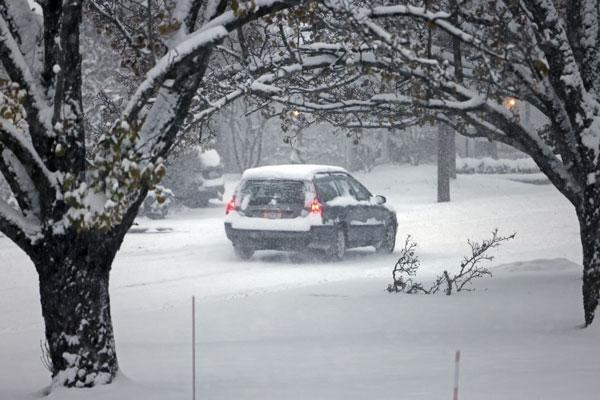 A car drives through the snow on E. Orange St. in Chagrin Fall, Ohio, Tuesday, Nov. 28, 2023. (Cleveland.com via AP)