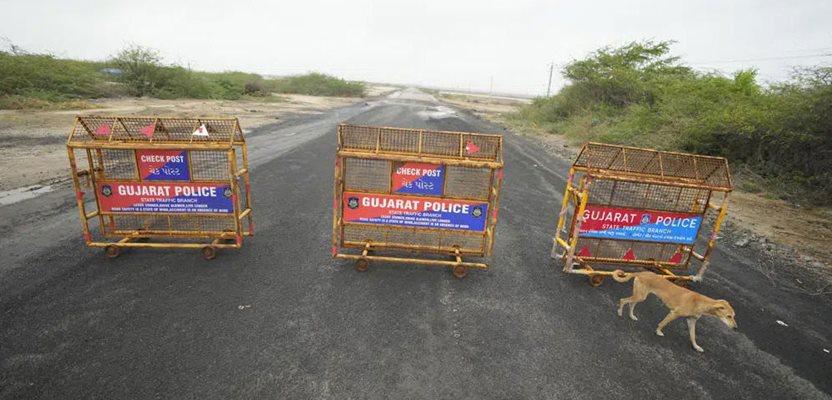 A dog walks past barricades placed on a road to Jakhau Port in Kutch district, India, Wednesday, June 14, 2023. (AP Photo/Ajit Solanki)