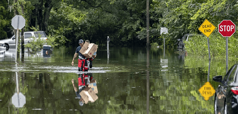 Savannah Fire Advanced Firefighters carry food to residents in the Tremont Park neighborhood that were stranded in flooding from T.S. Debby, Tuesday, August 6, 2024 in Savannah, Ga. (AP Photo/Stephen B. Morton)