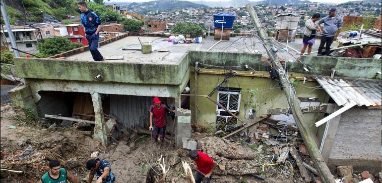 Locals work to clean up mud and debris around houses destroyed by a landslide after heavy rains in Vila Ideal neighborhood. (Credit: Alexandre Mota-Futura, AP)