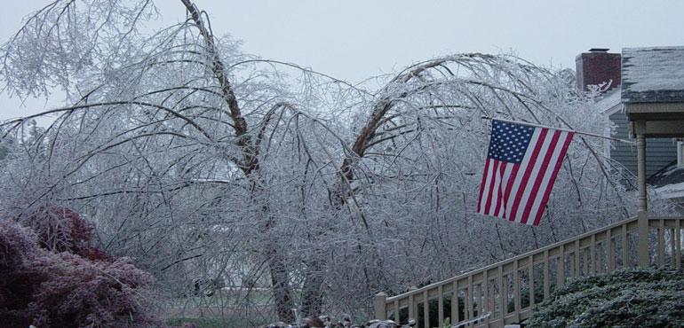 American flag hanging proudly from the porch of a home during a devastating ice storm. (Flickr via Wikimedia Commons)