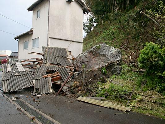 A rock sits on the ground near a house, following a landslide caused by the earthquake in Ohda, Shimane prefecture, western Japan, Monday, April 9, 2018. A strong earthquake in western Japan has cracked streets, cut water and power to a number of homes and caused slight injuries to five people. The Meteorological Agency said the magnitude 6.1 quake struck early Monday 12 kilometers (7 miles) underground near Ohda city, about 800 kilometers (480 miles) west of Tokyo. (Kyodo News via AP)