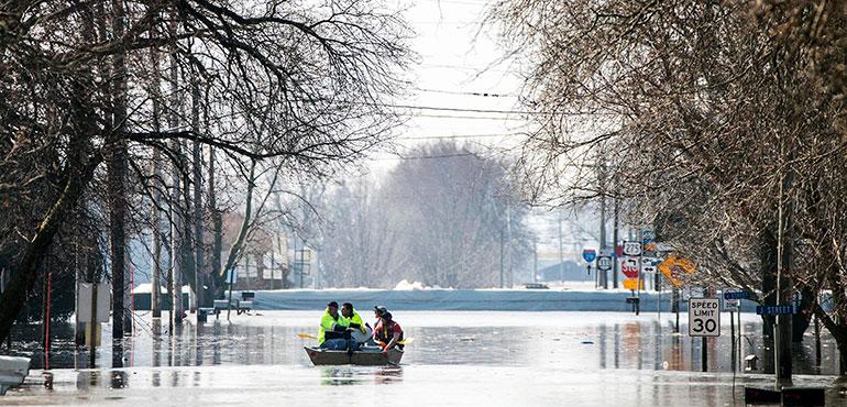 People on a boat float down floodwaters that cover Washington Street Wednesday, March 20, 2019, in Hamburg, Iowa. As some communities along the Missouri River start to shift their focus to flood recovery after a late-winter storm, residents in two Iowa cities are still in crisis mode because their treatment plants have shut down and they lack fresh water. (Chris Machian/Omaha World-Herald via AP)