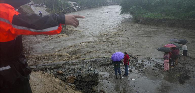 Residents stand alongside the banks of a river overrun by rains brought on by Tropical Storm Sara, on the outskirts of San Pedro Sula, Honduras, Saturday, Nov. 16, 2024. (AP Photo/Moises Castillo)