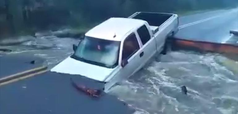 A truck is stuck after flooding washed a road away.
