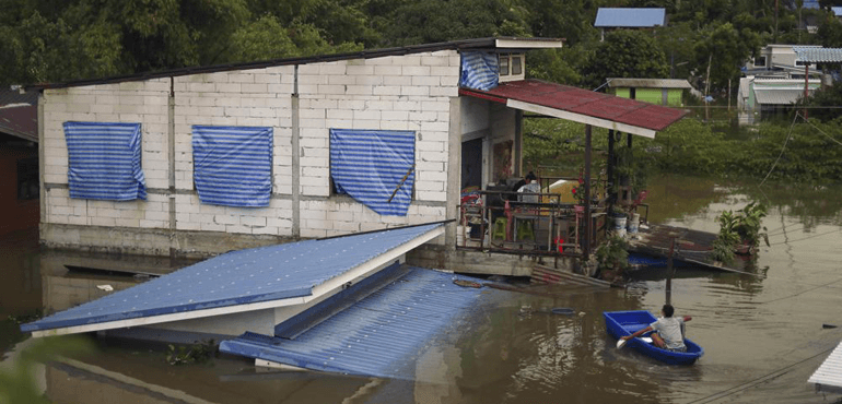 A resident paddles through floodwaters to reach the second story of his home in Ubon Ratchathani province, northeastern Thailand, Monday, Oct. 3, 2022. (AP Photo/Nava Sangthong)