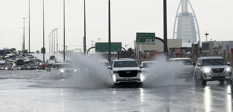 An SUV splashes through standing water on a road with the Burj Al Arab luxury hotel seen in the background in Dubai, UNited Arab Emirates, Tuesday, April 16, 2024. (AP Photo/Jon Gambrell)