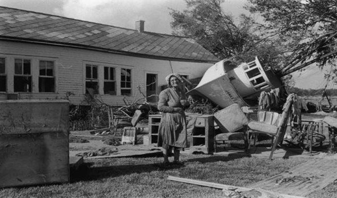 1957: An elderly woman in an apron and bonnet stands in front of a house, which was hit by a boat when Hurricane Audrey struck Louisiana. Shel Hershorn/Getty Images