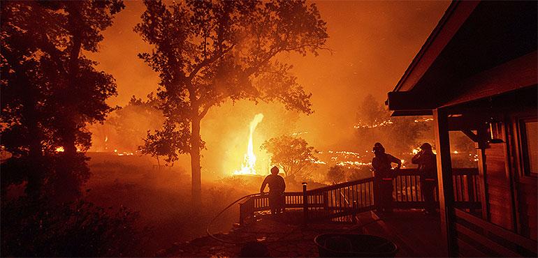 In this Aug. 21, 2020, file photo, firefighters watch flames from the LNU Lightning Complex fires approach a home in the Berryessa Estates neighborhood of unincorporated Napa County, Calif. (Noah Berger, AP)