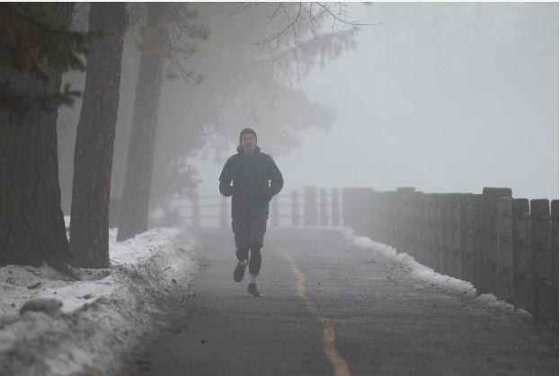 A person jogs along the Rideau Canal in Ottawa, on Saturday, Dec. 31, 2022. According to Environment Canada a rainfall and fog advisory is in effect for Ottawa and the surrounding regions calling for 20 to 30 mm of rain and reduced visibility. (Spencer Colby /The Canadian Press via AP)