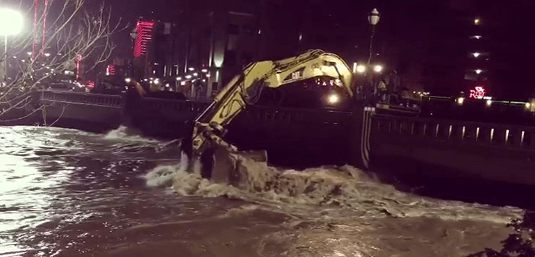 A large piece of machinery removes debris from the cresting Truckee River on Monday.