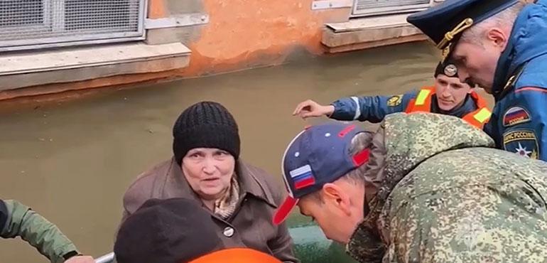Russian Emergency Situations Minister Alexnader Kurenkov, right speaks to a woman as emergency workers evacuate local residents with their pets after part of a dam burst causing flooding, in Orsk, Russia. (Russian Emergency Ministry Press Service via AP)