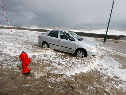 A car drives through flood waters in Wintrhrop, Mass., Saturday, March 3, 2018, a day after a nor'easter pounded the Atlantic coast with hurricane-force winds and sideways rain and snow, flooding streets, grounding flights, stopping trains and leaving 1.6 million customers without power from North Carolina to Maine. (AP Photo/Michael Dwyer)