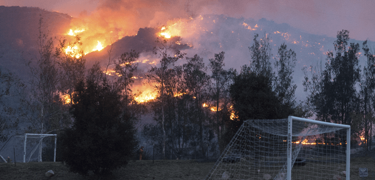 In this Sunday, Dec. 10, 2017, photo flames from a wildfire consume the mountainside near the Cate School campus in Carpinteria, Calif. (Kenneth Song/Santa Barbara News-Press via AP).