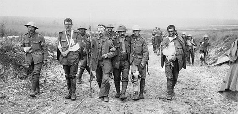 A German prisoner helps British wounded make their way to a dressing station near Bernafay Wood during the Battle of the Somme (Wikimedia Commons).