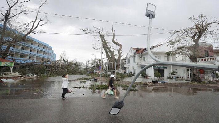 People walk past broken light post after typhoon Yagi hit the city, in Hai Phong, northern Vietnam on Sunday, Sept. 8, 2024. (Minh Quyet/VNA via AP)